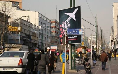 Iranians walk past a poster honoring the victims of a Ukrainian passenger jet accidentally shot down in the capital last week, in front of the Amirkabir University in the capital Tehran, on January 13, 2020.  (ATTA KENARE/AFP)