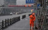 A worker wearing a protective facemask sweeps a street in Wuhan on January 25, 2020. (Hector Retamal/AFP)