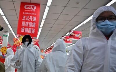 Pharmacy workers wearing protective clothes and masks serve customers in Wuhan on January 25, 2020 (Hector RETAMAL / AFP)