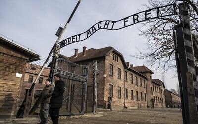Holocaust survivor and former prisoner of the Nazi death camp Auschwitz-Birkenau, Johnny (Ephroim) Jablon, left, crosses the gate with the inscription reading "Work sets you free" (Arbeit macht frei) in Oswiecim on January 26, 2020, one day before the 75th anniversary of its liberation. (Wojtek Radwanski/AFP)