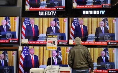 An Israeli man watches the televised press conference of US President Donald Trump and Prime Minister Benjamin Netanyahu at an electronics shop in the Israeli city of Modiin on January 28, 2020. (Gil Cohen-Magen/AFP)