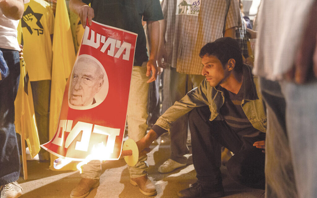 Assassin Yigal Amir, as portrayed by Yehuda Nahari Halev, torches a poster of Israeli Prime Minister Yitzhak Rabin in the film 'Incitement.' (Courtesy of PMKBNC/via JTA) Assassin Yigal Amir, as portrayed by Yehuda Nahari Halev, torches a poster of Israeli Prime Minister Yitzhak Rabin in the film 'Incitement.' (Courtesy of PMKBNC/via JTA)
