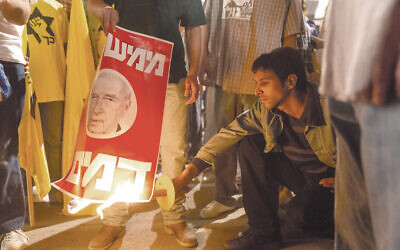 Assassin Yigal Amir, as portrayed by Yehuda Nahari Halev, torches a poster of Israeli Prime Minister Yitzhak Rabin in the film 'Incitement.' (Courtesy of PMKBNC/via JTA)