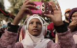 In this June 20, 2019 photo, a teenager films Sudanese dancers on her mobile phone during an event marking the UN's International Refugee Day, in Cairo, Egypt. (AP Photo/Maya Alleruzzo)