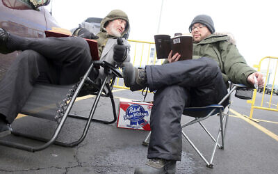 Rabbi Daniel Wasserman of Shaare Torah Congregation in Pittsburgh,, left, studies the Talmud with another man while tailgating in the parking lot of MetLife Stadium, Wednesday, Jan. 1, 2020, in East Rutherford, N.J., at an event called Siyum HaShas, that celebrates the completion of the reading of the Babylonian Talmud, a process that takes 7 1/2 years (AP Photo/Ted Shaffrey)