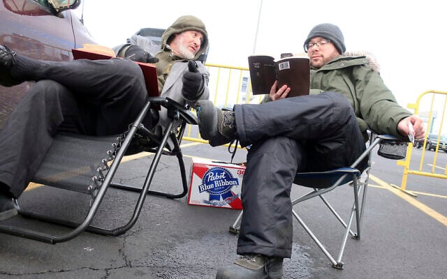 Rabbi Daniel Wasserman of Shaare Torah Congregation in Pittsburgh,, left, studies the Talmud with another man while tailgating in the parking lot of MetLife Stadium, Wednesday, Jan. 1, 2020, in East Rutherford, N.J., at an event called Siyum HaShas, that celebrates the completion of the reading of the Babylonian Talmud, a process that takes 7 1/2 years (AP Photo/Ted Shaffrey)