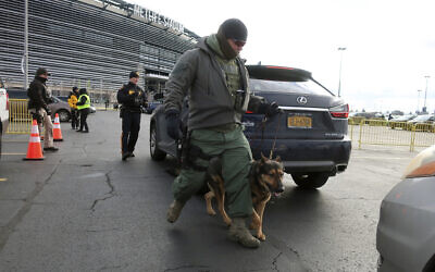 A law enforcement with a dog inspects vehicles parking at MetLife Stadium, Wednesday, Jan. 1, 2020, in East Rutherford, N.J., at an event called Siyum HaShas, that celebrates the completion of the reading of the Babylonian Talmud (AP Photo/Ted Shaffrey)