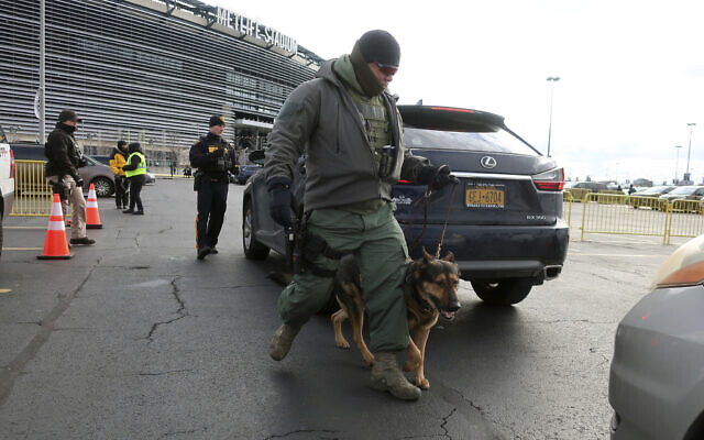 A law enforcement with a dog inspects vehicles parking at MetLife Stadium, Wednesday, Jan. 1, 2020, in East Rutherford, N.J., at an event called Siyum HaShas, that celebrates the completion of the reading of the Babylonian Talmud (AP Photo/Ted Shaffrey)