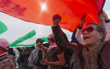 Anti government protesters chant anti-Iran and anti-US slogans under a big Iraqi flag that they carry during the ongoing protests in Tahrir square, Baghdad, Iraq, Friday, Jan. 10, 2020. (AP Photo/Nasser Nasser)