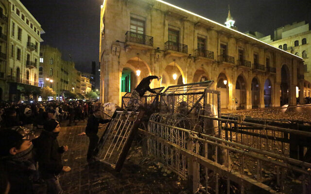 An anti-government protester stands on barriers as he throws stones at riot police during ongoing protests against the political elites who have ruled the country for decades, in Beirut, Lebanon, January 19, 2020. (Hassan Ammar/AP) An anti-government protester stands on barriers as he throws stones at riot police during ongoing protests against the political elites who have ruled the country for decades, in Beirut, Lebanon, January 19, 2020. (Hassan Ammar/AP)