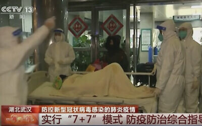In this Thursday, Jan. 23, 2020, image from China's CCTV video, a patient is carried on a stretcher to an ambulance by medical workers in protective suits in Wuhan, China.  (CCTV via AP)