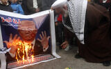 A Palestinian cleric burns a banner that shows a portrait of the U.S. President Donald Trump with Arabic words that read:"Your suspicious deal will not pass," during a protest against the White House plan for ending the Israeli-Palestinian conflict,  at Rashidiyeh Palestinian refugee camp, southern Lebanon on January 29, 2020.  (AP/Mohammed Zaatari)
