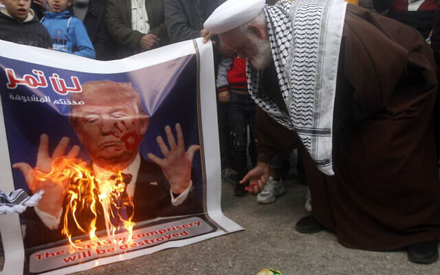 A Palestinian cleric burns a banner that shows a portrait of the U.S. President Donald Trump with Arabic words that read:"Your suspicious deal will not pass," during a protest against the White House plan for ending the Israeli-Palestinian conflict, at Rashidiyeh Palestinian refugee camp, southern Lebanon on January 29, 2020. (AP/Mohammed Zaatari) A Palestinian cleric burns a banner that shows a portrait of the U.S. President Donald Trump with Arabic words that read:"Your suspicious deal will not pass," during a protest against the White House plan for ending the Israeli-Palestinian conflict, at Rashidiyeh Palestinian refugee camp, southern Lebanon on January 29, 2020. (AP/Mohammed Zaatari)