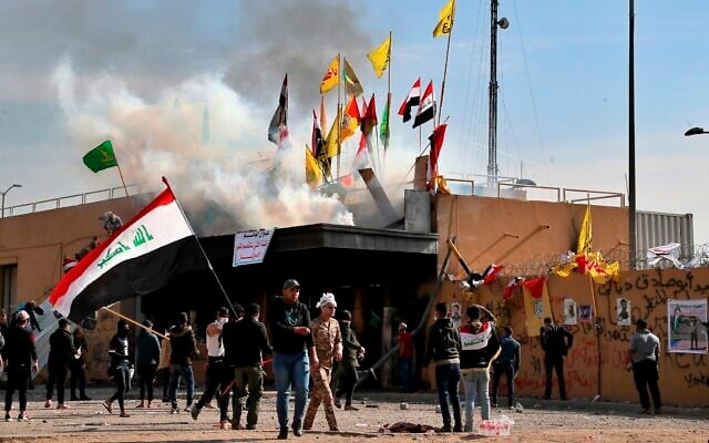 Pro-Iranian militiamen and their supporters set a fire while US soldiers fire tear gas during a sit-in in front of the US embassy in Baghdad, Iraq, January 1, 2020. (Khalid Mohammed/AP) Pro-Iranian militiamen and their supporters set a fire while US soldiers fire tear gas during a sit-in in front of the US embassy in Baghdad, Iraq, January 1, 2020. (Khalid Mohammed/AP)
