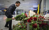 Ukrainian President Volodymyr Zelensky lays flowers at a memorial of the flight crew members of the Ukrainian 737-800 plane that crashed on the outskirts of Tehran, at Borispil international airport outside in Kyiv, Ukraine, January 9, 2020. (Ukrainian Presidential Press Office via AP)