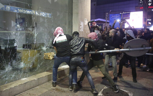 Anti-government protesters smash a bank widow, during ongoing protests against the Lebanese central bank's governor and against the deepening financial crisis, at Hamra trade street, in Beirut, Lebanon, January 14, 2020. (Hussein Malla/AP) Anti-government protesters smash a bank widow, during ongoing protests against the Lebanese central bank's governor and against the deepening financial crisis, at Hamra trade street, in Beirut, Lebanon, January 14, 2020. (Hussein Malla/AP)