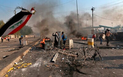 Anti-government protesters close a street while security forces use tear gas during clashes in central Baghdad, Iraq, Jan. 20, 2020 (AP Photo/Khalid Mohammed)