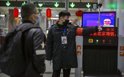 A security officer directs a man past a thermal imaging camera at a subway station in Beijing, January 29, 2020. (AP Photo/Mark Schiefelbein)
