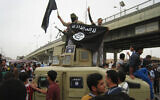 Illustrative: Islamic State fighters wave al-Qaeda flags as they patrol in a commandeered Iraqi military vehicle in Fallujah, Iraq on March 30, 2014. (AP Photo, File)