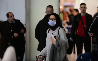 A woman wears a face mask in the arrivals hall of Ben Gurion Airport on January 28, 2020. (Tomer Neuberg/Flash90)