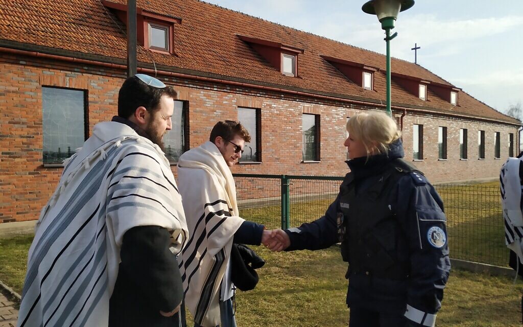 Rabbi Shabbos Kestenbaum shakes hands with a police officer after he and three others protested the location of a church in a former SS headquarters across from the former Nazi death camp Birkenau, January 27, 2020. (Yaakov Schwartz/ Times of Israel)