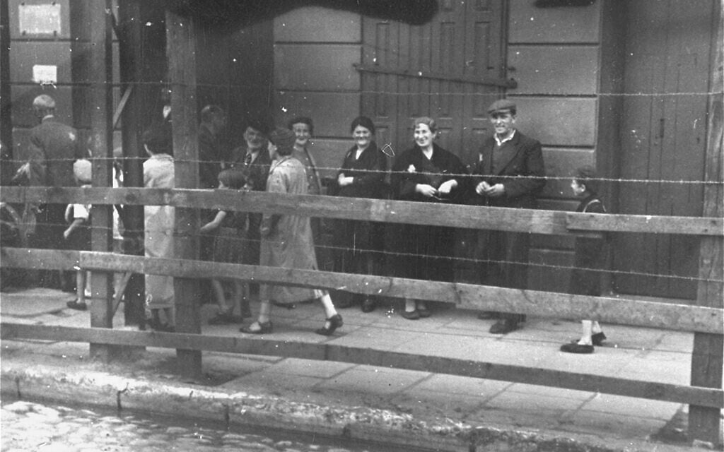 Lodz Ghetto Jews behind the wooden and barbed wire fence that separated the ghetto from the rest of the city, 1940-1941. (Courtesy of Daniel B. Schwartz)