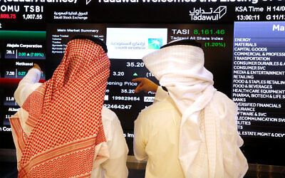 Saudi stock market officials watch the market screen displaying Saudi Arabia's state-owned oil company Aramco after its initial public offering (IPO) on the Riyadh's stock market in Riyadh, Saudi Arabia, Dec. 11, 2019. (AP Photo/Amr Nabil)