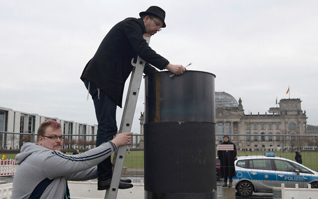 The author Eliyah Havemann reattaches a previously dismantled steel plate to the controversial steel column of the artists' collective 'Center for Political Beauty' (ZPS) opposite the Reichstag building in Berlin Germany, January 5, 2019. (Paul Zinken/dpa via AP) The author Eliyah Havemann reattaches a previously dismantled steel plate to the controversial steel column of the artists' collective 'Center for Political Beauty' (ZPS) opposite the Reichstag building in Berlin Germany, January 5, 2019. (Paul Zinken/dpa via AP)