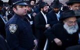 Illustrative: A New York City police officer watches as rabbis gather for a group photo at the Chabad-Lubavitch World Headquarters, in New York, November 4, 2018. (AP/Mark Lennihan)
