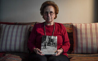 Greek Holocaust survivor Nina Camhi, 80, holds a book on the 'Holocaust of the Greek Jews' featuring her grandfather's bookstore in Thessaloniki, at her home in Athens, January 20, 2020. (Louisa Gouliamaki/AFP)