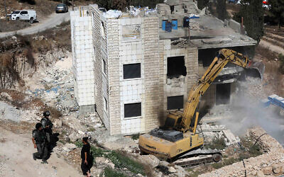 Israeli troops stand guard as bulldozers demolish a house in Hegrah Village in the West Bank, South Hebron, September 25, 2019. (Wisam Hashlamoun/Flash90)