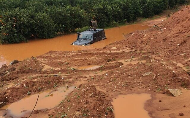 A soldier stands on the roof of his jeep after the vehicle got stuck in a deep puddle caused by recent rains in the central israeli town of Kfar Yona on January 20, 2020. (Israel Police) A soldier stands on the roof of his jeep after the vehicle got stuck in a deep puddle caused by recent rains in the central israeli town of Kfar Yona on January 20, 2020. (Israel Police)