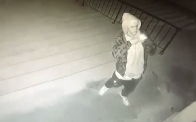 Security cam footage shows man taking photo after spraying swastika and racial epithets on stairs and door of a synagogue in Lincoln, Nebraska (video screenshot)