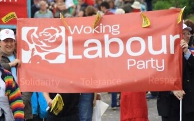 People hold a sign reading, 'Woking the Labour Party.' (via AJC)