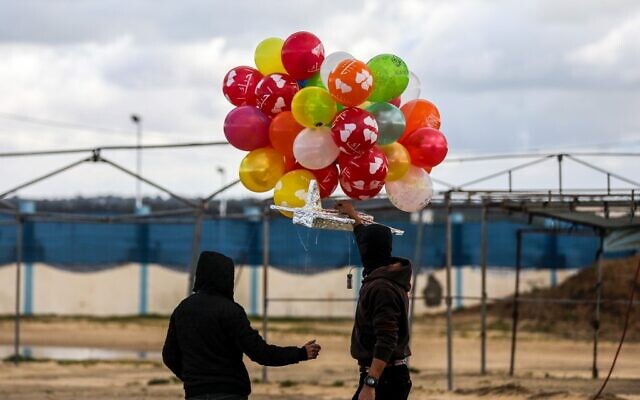 Masked Palestinians prepare to release an incendiary device near Gaza's Bureij refugee camp, along the Israel-Gaza border fence, on February 10, 2020. (MAHMUD HAMS / AFP) Masked Palestinians prepare to release an incendiary device near Gaza's Bureij refugee camp, along the Israel-Gaza border fence, on February 10, 2020. (MAHMUD HAMS / AFP)
