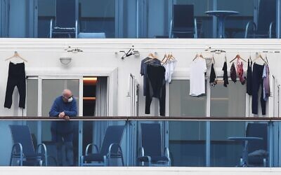 A passenger is seen on a balcony of the Diamond Princess cruise ship, with around 3,600 people quarantined onboard due to fears of the new coronavirus, at the Daikoku Pier Cruise Terminal in Yokohama port on February 14, 2020. (CHARLY TRIBALLEAU / AFP)