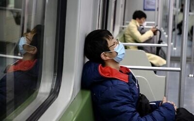 A subway passenger wearing a protective facemask sleeps on a train in Shanghai on February 14, 2020 (NOEL CELIS / AFP)