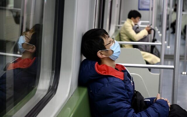 A subway passenger wearing a protective facemask sleeps on a train in Shanghai on February 14, 2020 (NOEL CELIS / AFP) A subway passenger wearing a protective facemask sleeps on a train in Shanghai on February 14, 2020 (NOEL CELIS / AFP)