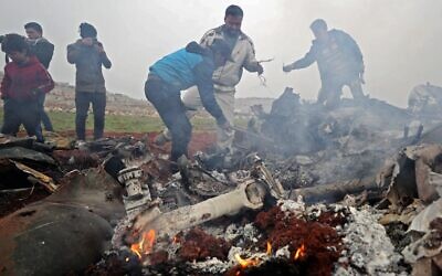 People search for scraps of metal among the debris of a Syrian military helicopter that was shot down on February 14, 2020, in the western countryside of Aleppo province. (Omar Haj Kadour/AFP)