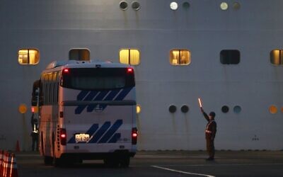 An Israeli flag can be seen in one of the portholes (left) of Diamond Princess cruise ship, where three Israelis have been diagnosed with coronavirus, at the Daikaku Pier Cruise Terminal in Yokohama port on February 16, 2020 (Behrouz MEHRI / AFP)