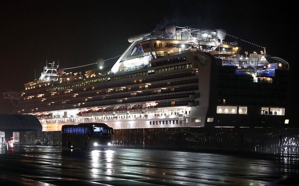 A bus carrying US citizens leaves the Daikaku Pier Cruise Terminal in Yokohama port, next to the Diamond Princess cruise ship, with people quarantined on board due to fears of the new COVID-19 coronavirus, February 17, 2020. (Behrouz Mehri/AFP)