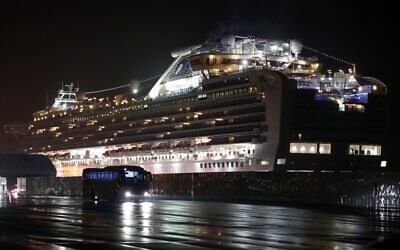 A bus carrying US citizens leaves the Daikaku Pier Cruise Terminal in Yokohama port, next to the Diamond Princess cruise ship, with people quarantined on board due to fears of the new COVID-19 coronavirus, February 17, 2020. (Behrouz Mehri/AFP)