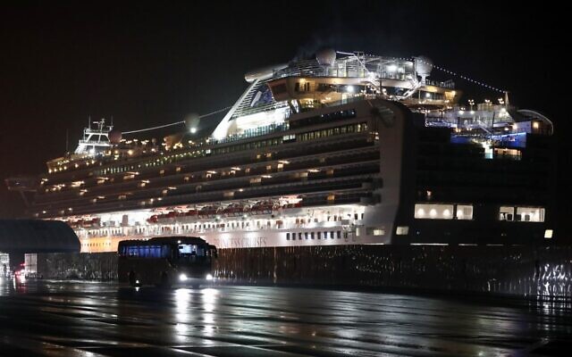 A bus carrying US citizens leaves the Daikaku Pier Cruise Terminal in Yokohama port, next to the Diamond Princess cruise ship, with people quarantined on board due to fears of the new COVID-19 coronavirus, February 17, 2020. (Behrouz Mehri/AFP)