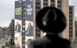 An ultra-Orthodox man walks near a Likud party billboard for Israel's upcoming general elections on February 17, 2020, showing the portraits of (L to R) Benny Gantz, head of the Blue and White political alliance and Ahmad Tibi, Knesset member for the Joint List, with a caption reading, 'Gantz has no government without Tibi.' (Ahmad Gharabli/AFP)