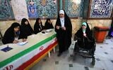 Iranian voters check a list of candidates before casting their ballot during parliamentary election at a polling station in Tehran on February 21, 2020. (Photo by ATTA KENARE / AFP)