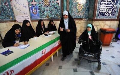 Iranian voters check a list of candidates before casting their ballot during parliamentary election at a polling station in Tehran on February 21, 2020. (Photo by ATTA KENARE / AFP)
