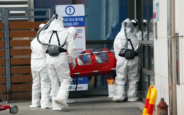 Medical workers wearing protective gear carry a patient infected with the COVID-19 coronavirus at a hospital in Chuncheon, South Korea, February 22, 2020. (Yonhap/AFP)
