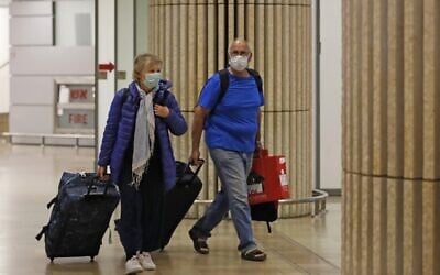 Passengers wearing protective masks walk through the arrival hall of Ben Gurion Airport on February 22, 2020. (Ahmad Gharabli/AFP)