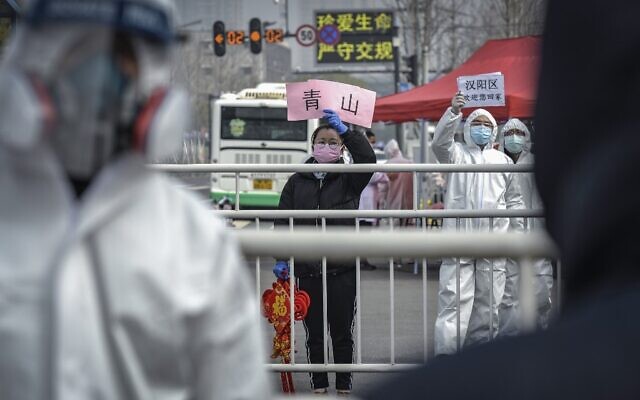 This photo taken on February 22, 2020 shows a woman welcoming people who have recovered from the COVID-19 coronavirus infection as they are discharged from the hospital in Wuhan in China's central Hubei province. (Photo by STR / AFP) This photo taken on February 22, 2020 shows a woman welcoming people who have recovered from the COVID-19 coronavirus infection as they are discharged from the hospital in Wuhan in China's central Hubei province. (Photo by STR / AFP)
