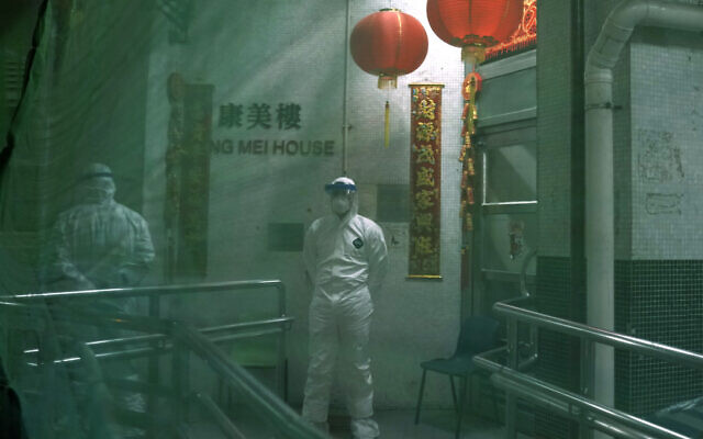 Personnel wearing protective suits wait near an entrance at the Cheung Hong Estate, a public housing estate during evacuation of residents in Hong Kong, February 11, 2020. (Kin Cheung/AP) Personnel wearing protective suits wait near an entrance at the Cheung Hong Estate, a public housing estate during evacuation of residents in Hong Kong, February 11, 2020. (Kin Cheung/AP)